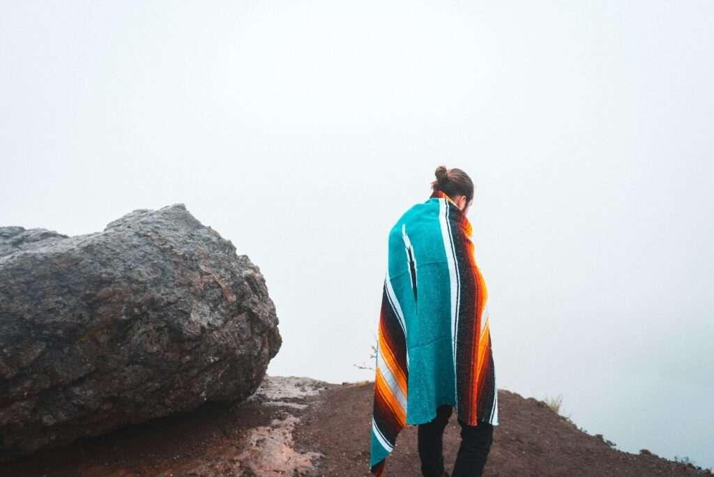 Person standing beside black rock