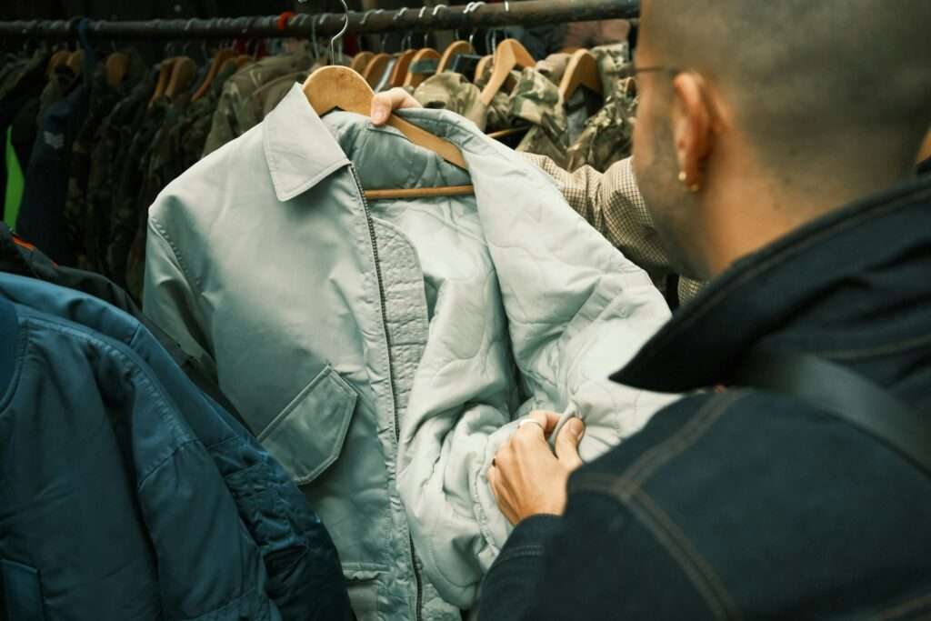 Man standing in front of a rack of clothes image